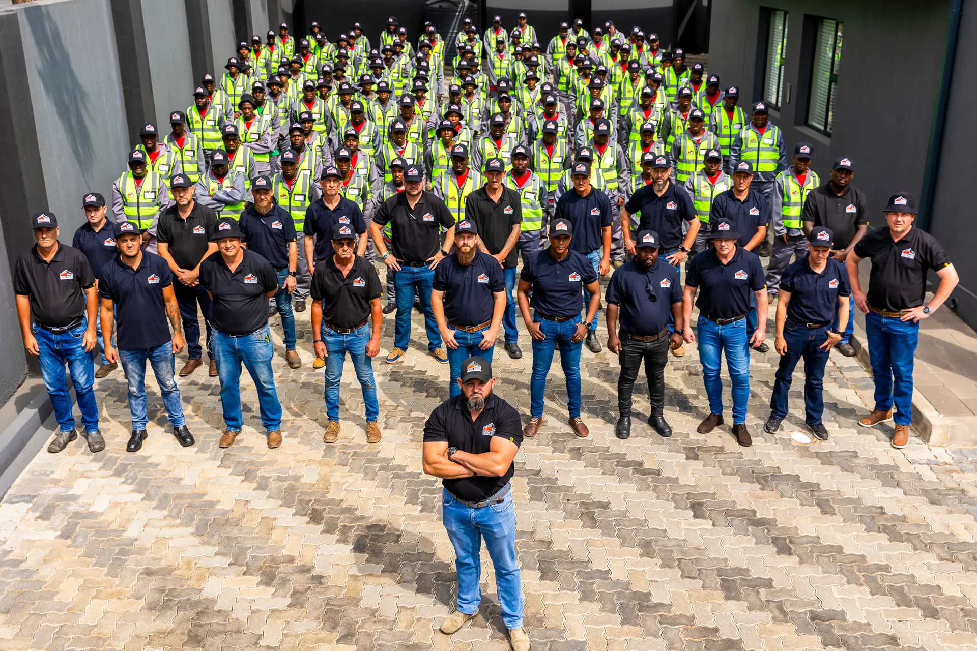 A professional skilled construction team and their management stand proudly in front of a modern building, ready for new projects.