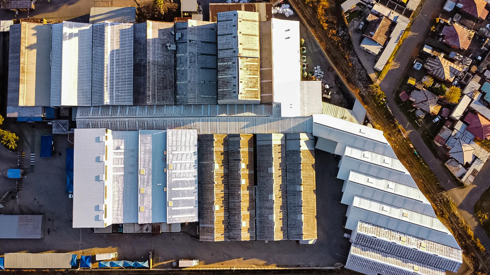 Aerial top-down view showcasing a large industrial complex with various factory and warehouse roofs alongside residential buildings.